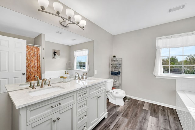 bathroom with a sink, toilet, wood finished floors, and visible vents