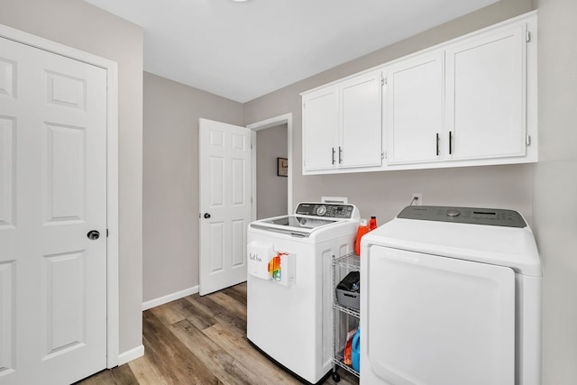 washroom featuring washer and dryer, baseboards, light wood finished floors, and cabinet space