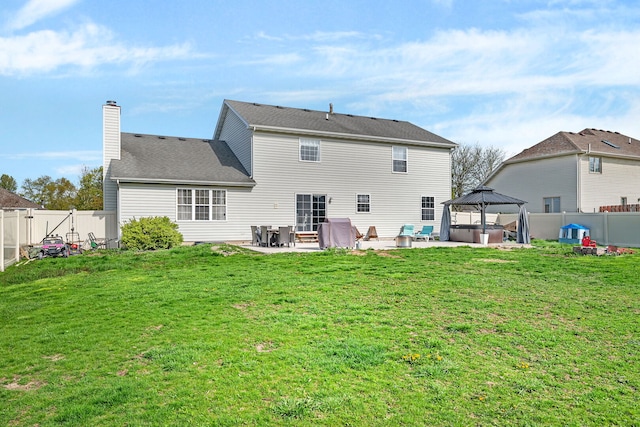 back of house featuring a hot tub, a patio, a yard, and a fenced backyard