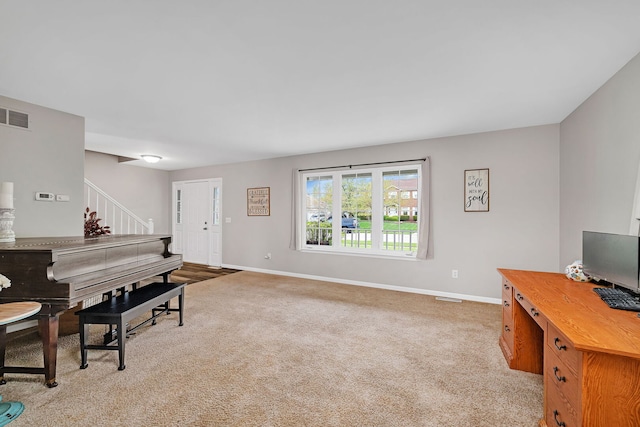 living area featuring baseboards, visible vents, light carpet, and stairway
