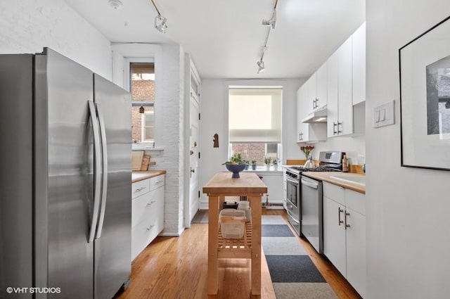 2311 N Commonwealth Ave Unit 3E, Chicago, IL 60614 - kitchen with track lighting, white cabinets, under cabinet range hood, stainless steel appliances, and light wood-style flooring