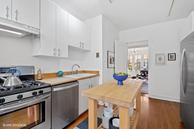 2311 N Commonwealth Ave Unit 3E, Chicago, IL 60614 - kitchen featuring appliances with stainless steel finishes, a sink, light countertops, wood finished floors, and under cabinet range hood