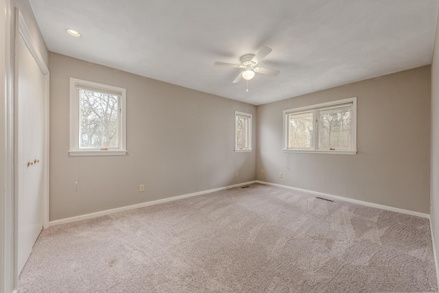 carpeted spare room featuring baseboards, ceiling fan, and visible vents