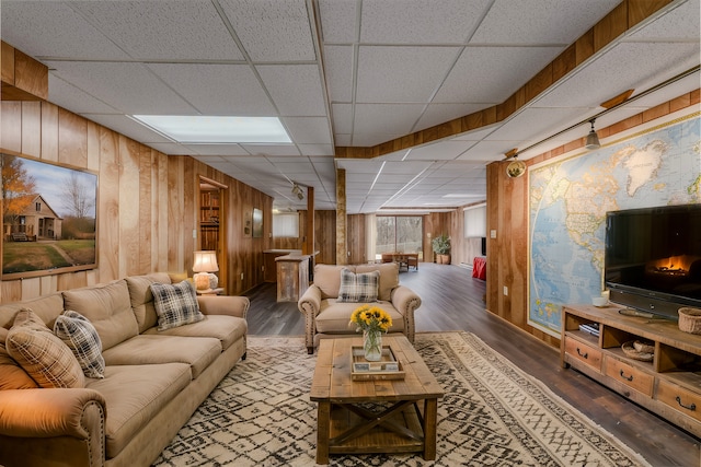 living area featuring wood walls, a drop ceiling, and wood finished floors