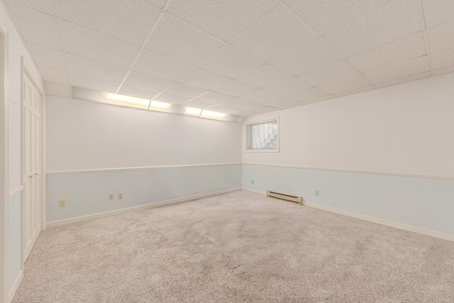 spare room featuring baseboards, a drop ceiling, baseboard heating, and carpet