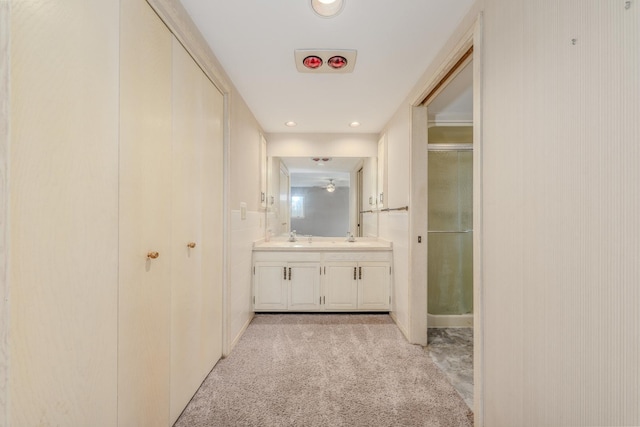 hallway with recessed lighting, light colored carpet, and a sink