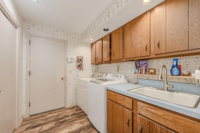 laundry area with washer and dryer, cabinet space, a sink, light wood-style flooring, and wallpapered walls