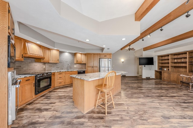 kitchen with wood finished floors, a kitchen island, custom exhaust hood, and black appliances