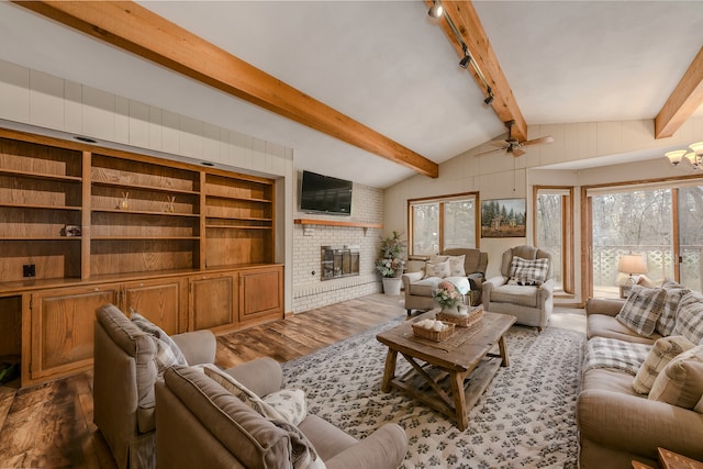 living room featuring a fireplace, ceiling fan, lofted ceiling with beams, and dark wood finished floors