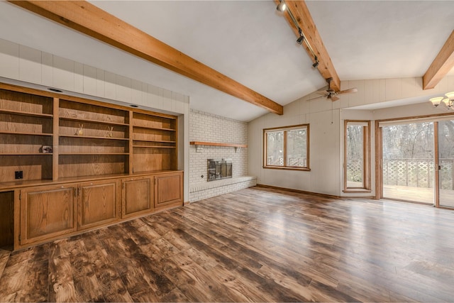 unfurnished living room featuring track lighting, a ceiling fan, a fireplace, dark wood-type flooring, and lofted ceiling with beams
