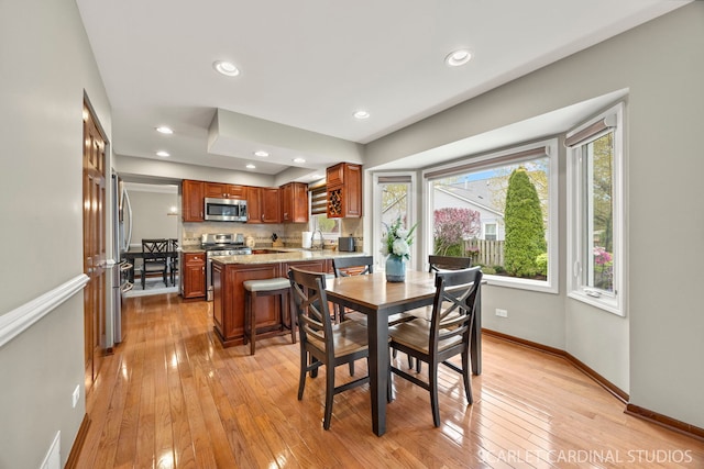 dining room with baseboards, light wood-type flooring, and recessed lighting