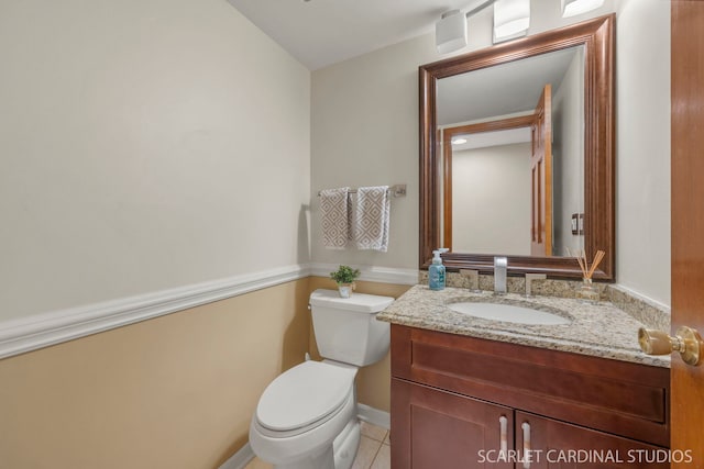 half bathroom with toilet, baseboards, tile patterned flooring, and vanity