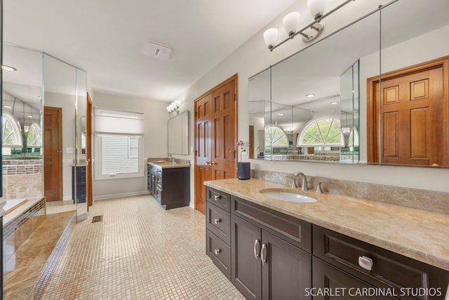 bathroom featuring a healthy amount of sunlight, two vanities, and a sink