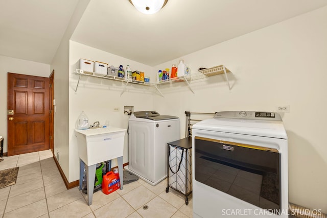laundry room with washing machine and clothes dryer, laundry area, light tile patterned floors, and a sink