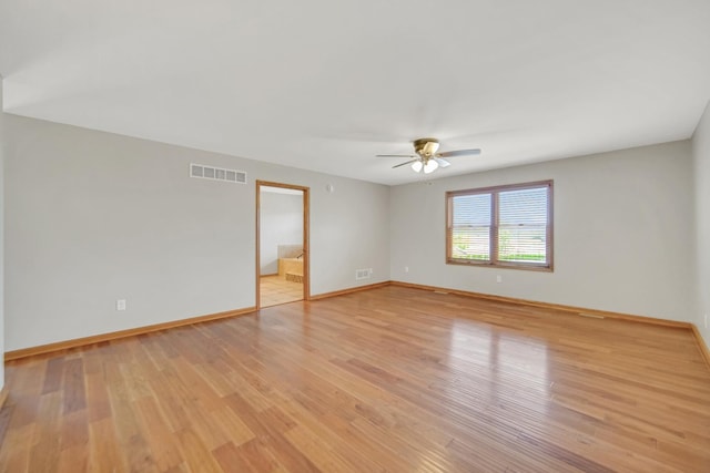 spare room featuring a ceiling fan, baseboards, visible vents, and light wood finished floors