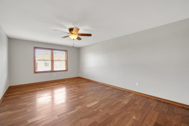 spare room with baseboards, ceiling fan, and wood finished floors