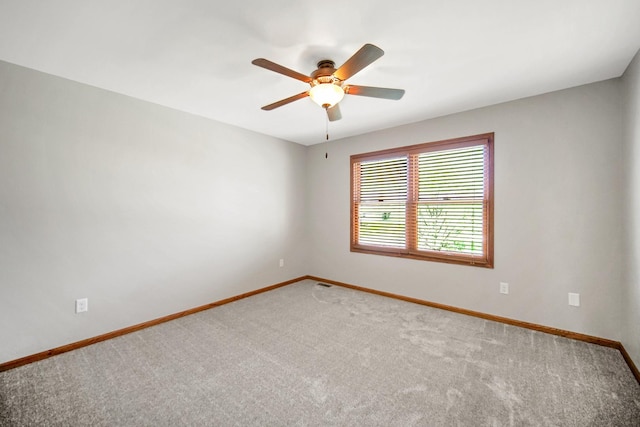 spare room with carpet floors, ceiling fan, baseboards, and visible vents
