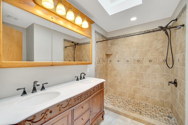 full bath featuring tiled shower, a skylight, visible vents, and a sink
