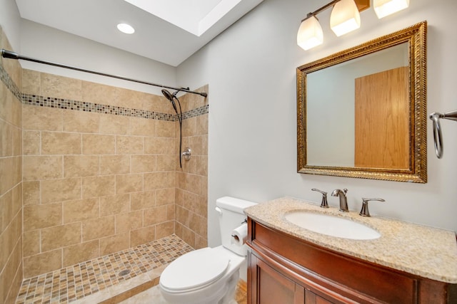 full bathroom with toilet, a skylight, tiled shower, and vanity