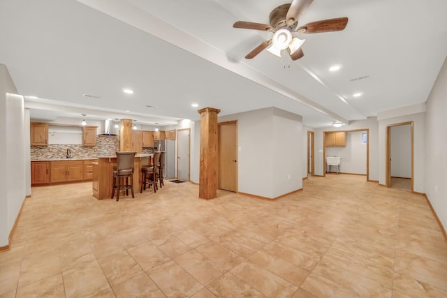 living area featuring baseboards, a ceiling fan, and wet bar