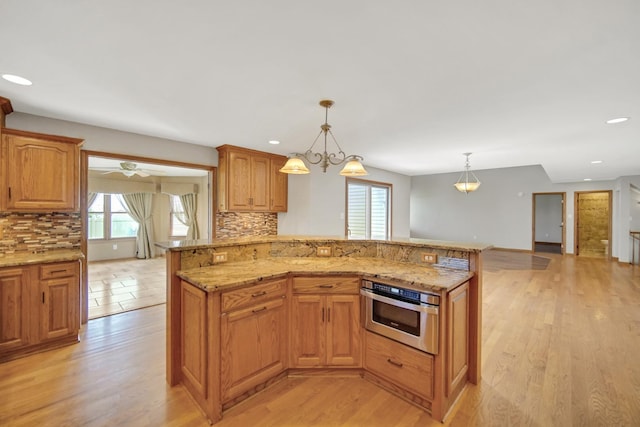 kitchen featuring oven, light wood-style floors, light stone counters, and tasteful backsplash