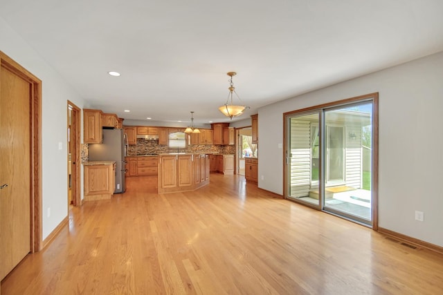 kitchen featuring recessed lighting, tasteful backsplash, freestanding refrigerator, and light wood-type flooring