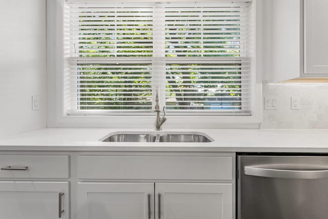 kitchen featuring dishwasher, a sink, light countertops, decorative backsplash, and white cabinetry