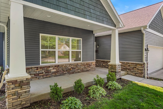 property entrance featuring covered porch, stone siding, a garage, and a shingled roof