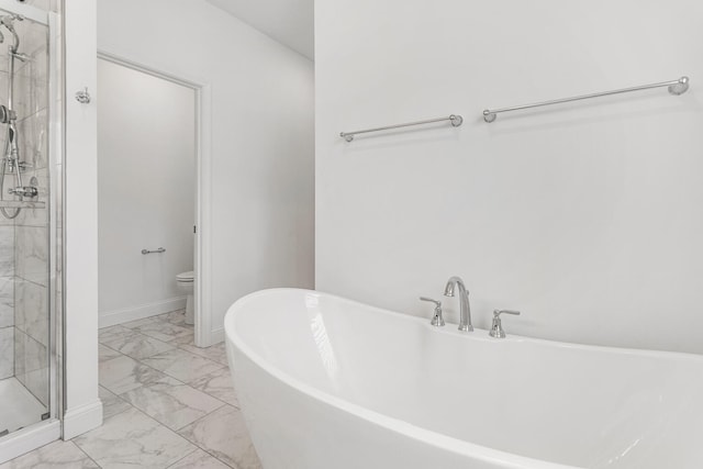 bathroom with marble look tile flooring, a stall shower, toilet, a freestanding tub, and baseboards