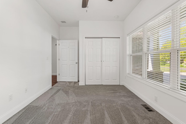 unfurnished bedroom featuring carpet, multiple windows, a closet, and baseboards
