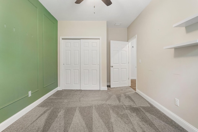 unfurnished bedroom with a closet, carpet floors, baseboards, and ceiling fan