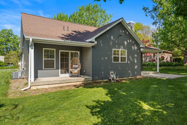 rear view of property featuring central air condition unit, a lawn, a chimney, a patio area, and covered porch