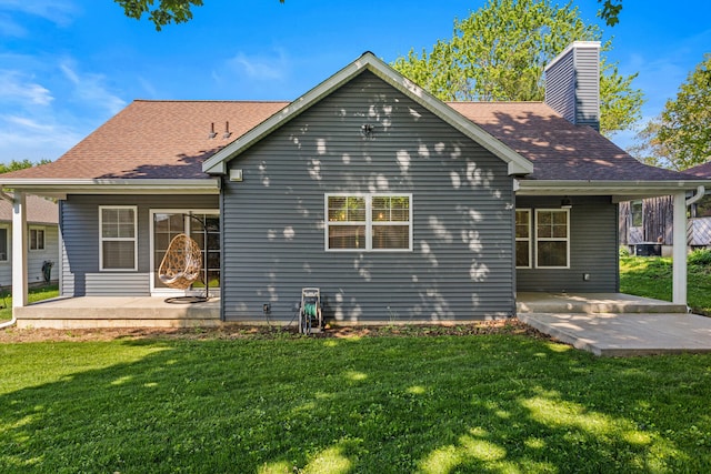back of house with a yard, a patio, a chimney, and a shingled roof