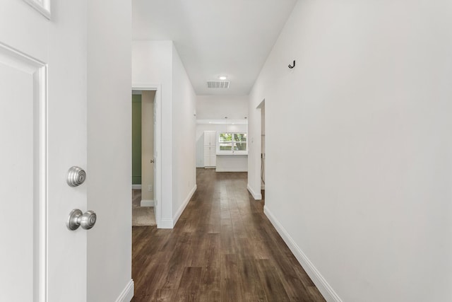 hall featuring dark wood-type flooring and baseboards