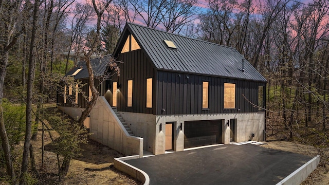 view of front of property with asphalt driveway, board and batten siding, stairway, an attached garage, and metal roof