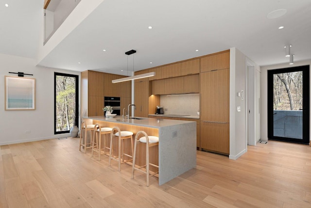 kitchen with modern cabinets, a sink, light wood-style flooring, light countertops, and recessed lighting
