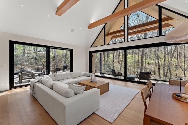 living area featuring high vaulted ceiling, plenty of natural light, hardwood / wood-style flooring, and beam ceiling