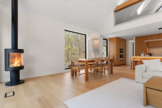 dining space featuring light wood-style floors, a towering ceiling, and baseboards