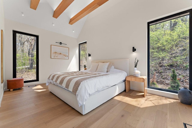 bedroom with light wood-style flooring, beam ceiling, multiple windows, and high vaulted ceiling