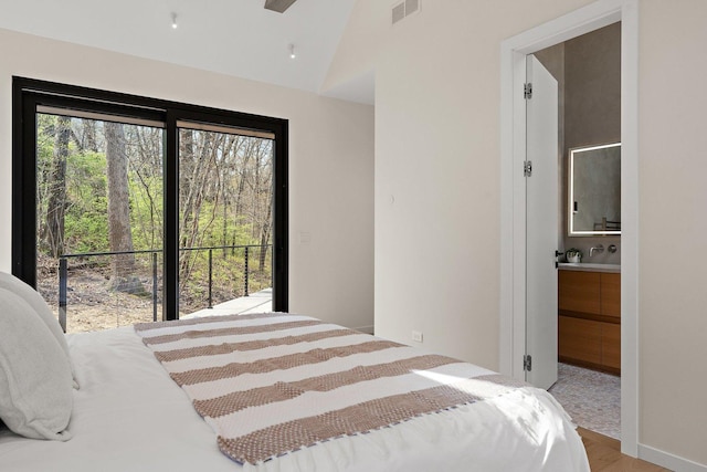 bedroom featuring lofted ceiling, wood finished floors, and ensuite bathroom