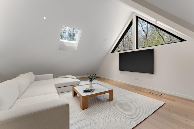 living area featuring a skylight, wood finished floors, and baseboards