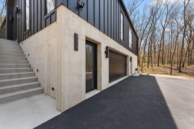 view of side of property featuring stairway, driveway, a garage, and board and batten siding