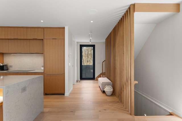 corridor featuring light wood-type flooring, recessed lighting, and stairs