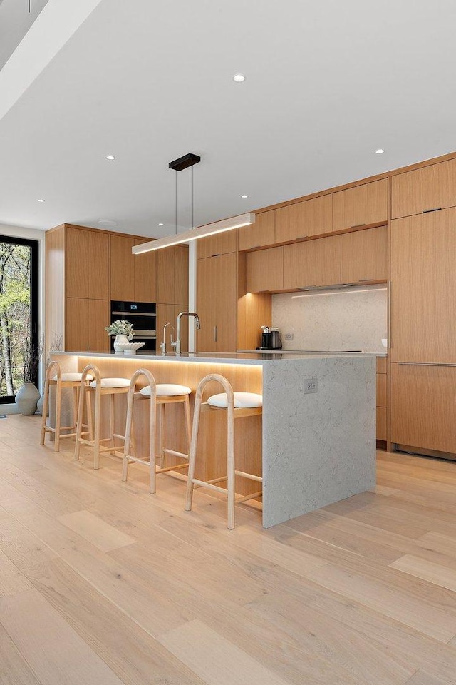 kitchen featuring modern cabinets, light wood finished floors, a breakfast bar, and recessed lighting