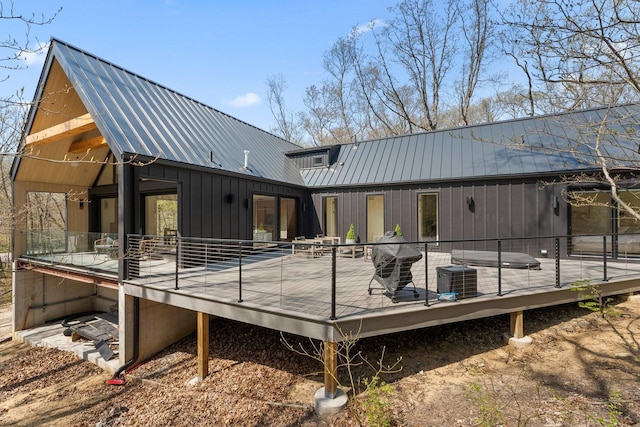 rear view of property with metal roof, a wooden deck, and central AC unit