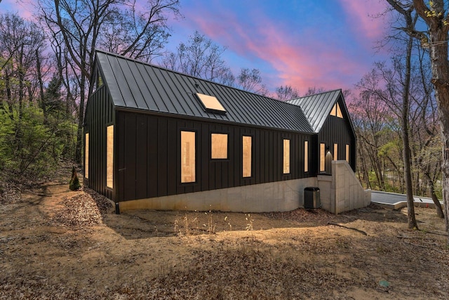 view of home's exterior featuring a standing seam roof, board and batten siding, metal roof, and central air condition unit