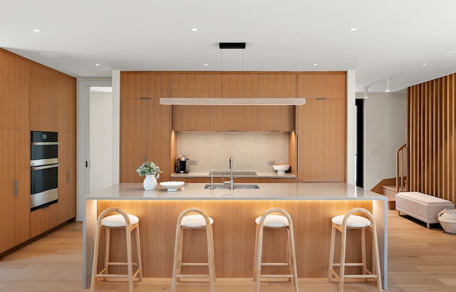 kitchen with a sink, modern cabinets, light wood-style floors, and recessed lighting
