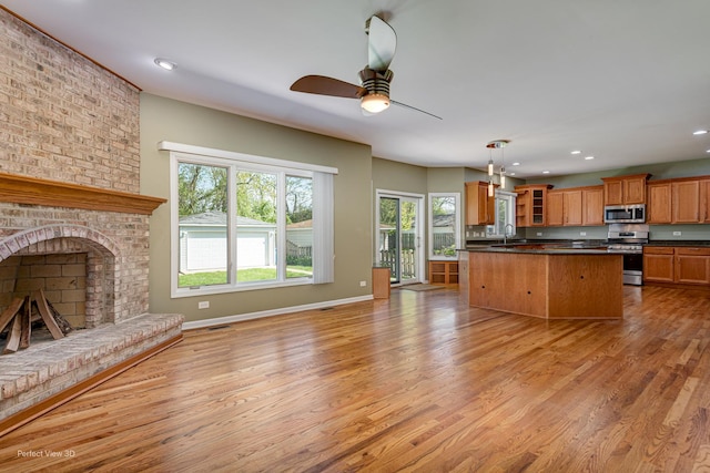 573 W Babcock Ave, Elmhurst, IL 60126 - kitchen with appliances with stainless steel finishes, dark countertops, light wood-style floors, a brick fireplace, and a ceiling fan