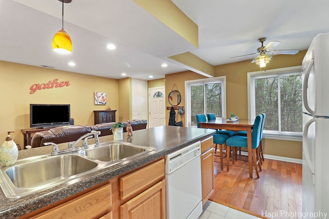 kitchen featuring visible vents, pendant lighting, dark countertops, white appliances, and a sink