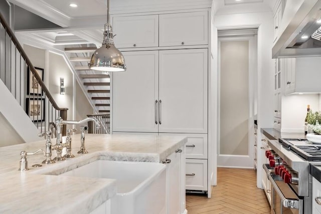 kitchen featuring pendant lighting, range hood, light stone countertops, stainless steel range, and white cabinetry